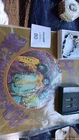 Photo shows the Jimi Hendrix vinyl album with a psychedelic purple and brown cover as well as several jewelry boxes containing various pieces of costume jewelry including a silver-tone bracelet.