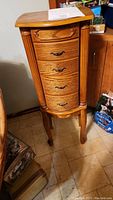 Full view of the wooden jewelry chest showing four drawers and legs.