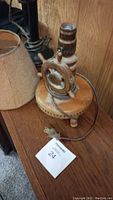 Old phone style lamp with wooden and cream colored parts, on a wooden base, with a power cord and plug.