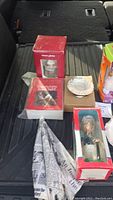 Lot of seven miscellaneous unopened collectibles including vintage book light, snow globe, Ichiro bobblehead, Furby, JFK doll and other small items shown arranged together.