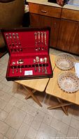 Full view of flatware set in red velvet-lined case on table with two cut glass bowls beside it