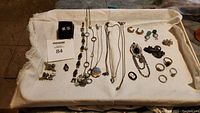 Full set of silver tone jewelry items arranged on white cloth showing earrings, necklaces, rings, brooches, cameo, and penguin figurine