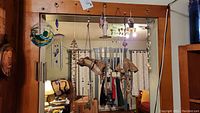 Wide view showing 9 wind chimes with different materials hanging from a wooden frame and a tree branch decoration indoors
