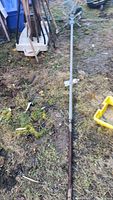 Full view of 11 ft 3 in brass weather vane lying on the ground, some rust visible on pole.