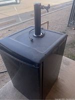 Front-side view of black Danby mini refrigerator with tap on top, showing general shape and exterior condition.
