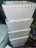 Four small white foam coolers stacked, showing textured foam bead surface and lids.
