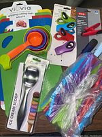 Photo showing entire lot including colorful cutting mats, measuring cups, ice cream scoop, magnetic clips, and straws.