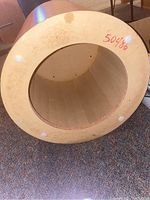 Bottom view of the round wooden table showing the hollow interior and protective padding on the base