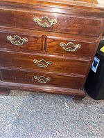 Front angled view of the Thomasville wooden end table showing four drawers with brass handles and some wear on the top surface