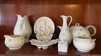 Full view of 8-piece Belleek serving ware including vases, jug, lidded basket, decorative plate and pottery pieces with shamrock motif