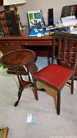Vintage Legomatic folding chair with red cushioned seat and dark wood frame alongside wooden pie crust table with rounded tray top and tripod base