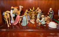 Full view of all porcelain nativity figurines arranged on shelf.