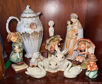 Wide view of all figurines arranged on a wood shelf showing variety and scale
