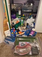 Overview showing assortment of cleaning and personal care items with brooms and blue Swiffer tool in a closet corner.