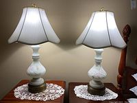 Both lamps illuminated on side tables showing full lamp appearance, shades, and painted floral bases.