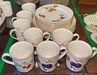 Photo showing 21 pieces of Royal Worcester Evesham porcelain including mugs and plates with fruit motifs and gold rims.