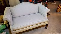 Front view of camel back upholstered settee showing patterned fabric and shape