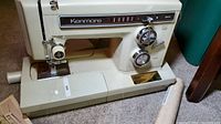 Front view of the Kenmore sewing machine showing control dials, stitch pattern selector, and needle area with presser foot.