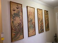 Four bamboo-style framed Asian art prints hung on a wall, showing vertical detailed paintings of birds and flowers.