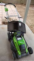 Full view of Greenworks electric mower showing black fabric collection bag and wheels, mower handle, and control panel.