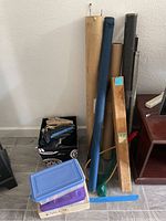 Photo showing fishing poles in protective tubes, gloves on top of a box, and plastic totes stacked on floor.
