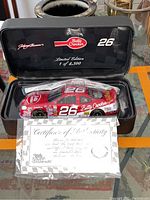 Closed black display case showing interior lid with Betty Crocker logo, number 26, and Limited Edition 1 of 4,500 marking, containing red Betty Crocker #26 NASCAR model car and Certificate of Authenticity in front.