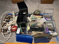 Wide view showing desk organizers, staplers, pens, cables, power strips, deposit bags, and assorted office supplies on carpet.