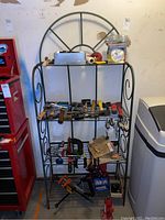 Full view of metal decorative plant stand holding various hand tools and items on multiple shelves.