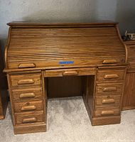 Full front view of the oak roll top desk showing the closed tambour roll top and drawer configuration.