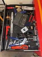 Photo of top drawer containing mostly pliers, cutters, screwdrivers and a socket wrench set