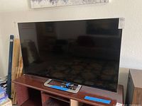 Front view of 60-inch Vizio flat screen TV on wooden stand, screen off.