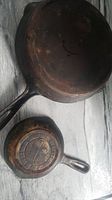 Two cast iron pans shown from top view on grey surface. Size difference visible.
