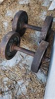 Photo showing two rusty 8-pound dumbbells on a rustic floor with dry pine needles around.