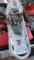 Top side of one aluminum Atlas X Series snowshoe showing bindings, straps, and logo