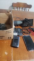 Overview of the lot items on the table showing Garmin GPS devices, 4 cell phones, mouse, and cables