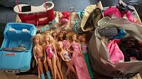 Photo showing the full lot including all dolls, the blue Barbie Jeep, the toy dental chair, blender, toaster, bike, and bag of clothes and accessories.
