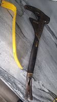 Two pry bars on a surface: the black-handled, toothed Stanley bar and the yellow metal bar.