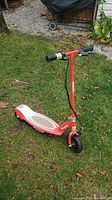 Front and upper side view of the red Razor Electric Scooter 2 showing the handlebar, deck, and front wheel on the grass.