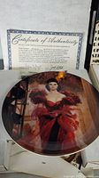 Photo of Scarlett's Resolve plate featuring Scarlett O'Hara in red dress and certificate of authenticity.