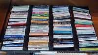 Overall view of the cassette singles lot, showing multiple rows of cassette cases in the holder.