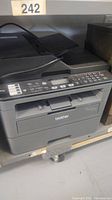 Full view of Brother MFC-L2710DW printer showing physical keypad, control panel, paper output tray and top document feeder