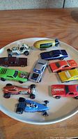 Top down view of all 11 Hot Wheels cars on a white plate showing colors and models