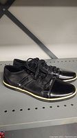 Full side view of left and right Kenneth Cole men's black casual shoes on shelf.