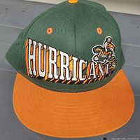 Front view of the Miami Hurricanes vintage snapback hat showing the green crown, orange brim, and embroidered Hurricanes text and mascot.