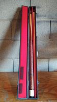 Full view of the pool cue and case inside the open case showing the full length of the cue stored inside.