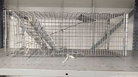 Rectangular metal wire mesh rodent cage viewed from the side, showing wire mesh construction, metal frame, and door with latch.