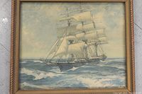 Full view of framed ship at sea artwork showing three-masted ship with sails unfurled on a daytime ocean background.