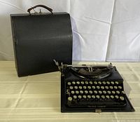 Front view of the typewriter with original carrying case, case closed and standing upright.