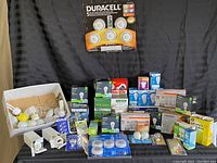 Photo showing assortment of light bulbs, battery-operated push lights, boxed and loose.