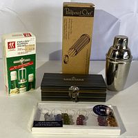 Photo of all items showing the martini shaker, boxed corkscrew, butter cutter box, bread tube box, and wine glass charms in packaging.